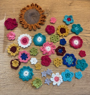 Kleurrijke gehaakte bloemen op een houten ondergrond