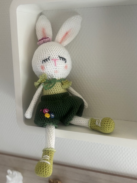 Gehaakt konijntje met groene rok op een plank